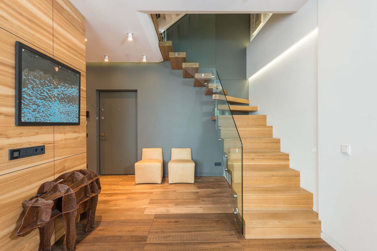 Entrée d'un appartement : parquet, escalier de bois clair et porte palière